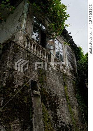 The old, dirty shabby facade of the building in the park 127503198