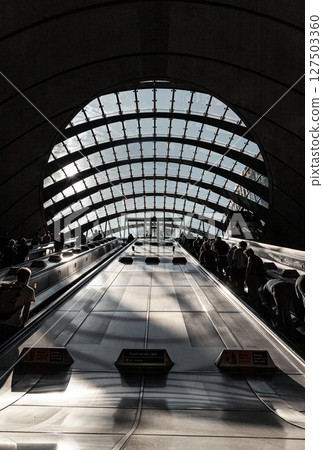 People and travelers utilizing the escalators within Canary Wharf tube station. 127503360
