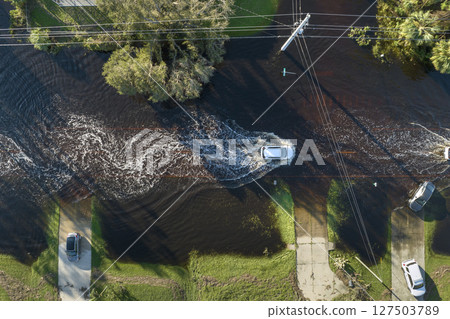 Flooded Florida road with evacuating cars and surrounded with water houses in suburban residential area. Consequences of hurricane natural disaster Flooded Florida road with evacuating cars and surrounded with water houses in suburban residential area. Consequences of hurricane natural disaster 127503789