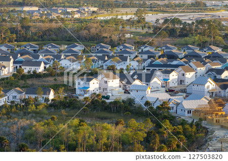 Development of residential housing in the USA. Wooden frames of new cheap American homes under construction Development of residential housing in the USA. Wooden frames of new cheap American homes under construction 127503820