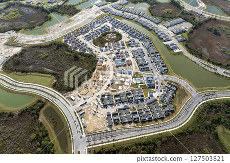 Development of residential housing in the USA. Wooden frames of new cheap American homes under construction Development of residential housing in the USA. Wooden frames of new cheap American homes under construction 127503821