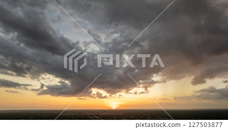 Colorful sunset sky with setting sun behind vivid orange and yellow clouds 127503877