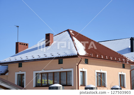 Closeup of house roof top covered with snow in cold winter. Tiled covering of building in wintertime weather Closeup of house roof top covered with snow in cold winter. Tiled covering of building in wintertime weather 127503903