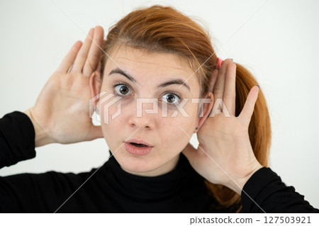 Close up portrait of funny girl holding her ears with hands like a monkey. Close up portrait of funny girl holding her ears with hands like a monkey. 127503921