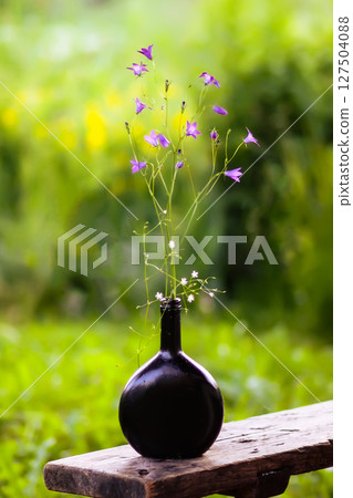 Beautiful bouquet of mixed summer flowers in a black vase. Floral decor outdoors on the wooden bench. Beautiful bouquet of mixed summer flowers in a black vase. Floral decor outdoors on the wooden bench. 127504088