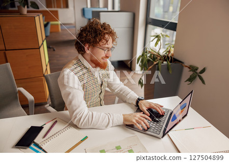 A Creative Professional is Engaged with Their Laptop in a Stylish and Modern Office Space 127504899