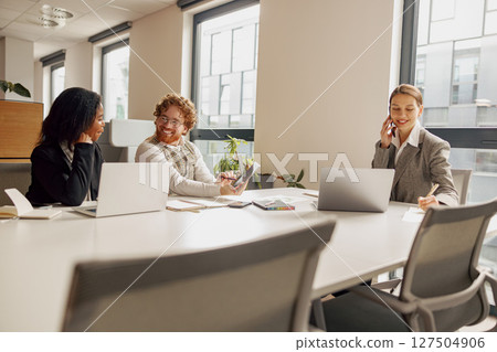 Professional women are effectively collaborating in a modern and vibrant office space setting 127504906