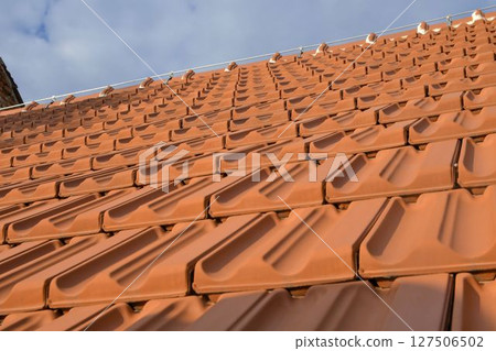 Newly covered roof. New roofing with terracotta tiles. Concept of construction and building works Newly covered roof. New roofing with terracotta tiles. Concept of construction and building works 127506502