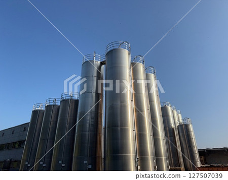 Large industrial building with many tall tanks Large industrial building with many tall tanks 127507039