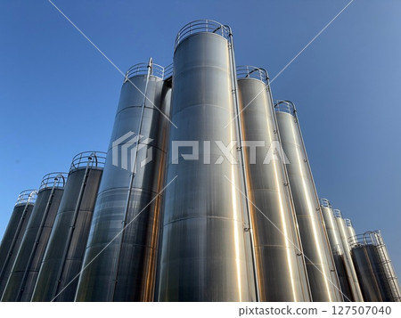 Large stack of metal tanks with a blue sky in the background Large stack of metal tanks with a blue sky in the background 127507040