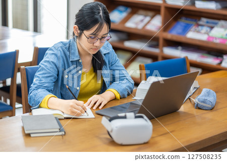 Student Studying with Laptop in Library Setting Student Studying with Laptop in Library Setting 127508235