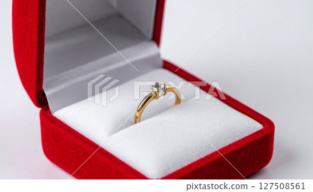 Golden ring placed on a satin miniature pillow in a red soft open box Golden ring placed on a satin miniature pillow in a red soft open box 127508561
