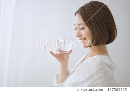 Young woman drinking water in the living room Young woman drinking water in the living room 127509635