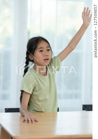 Young Girl Raising Her Hand in a Classroom During an Interactive Learning Session With Peers on a Sunny Day Young Girl Raising Her Hand in a Classroom During an Interactive Learning Session With Peers on a Sunny Day 127509857