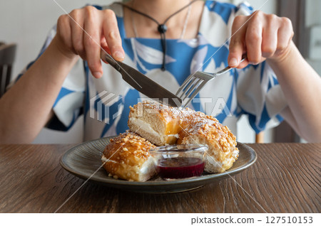 Cropped shot view of someone cutting a slice of almond Bezel bun for eat. Cropped shot view of someone cutting a slice of almond Bezel bun for eat. 127510153