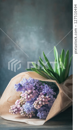 Bouquet of beautiful flowers wrapped in paper on a rustic wooden table 127510494
