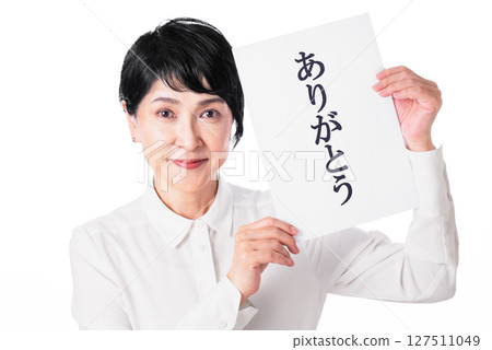 A smiling middle-aged woman holding a piece of paper that says thank you A smiling middle-aged woman holding a piece of paper that says thank you 127511049