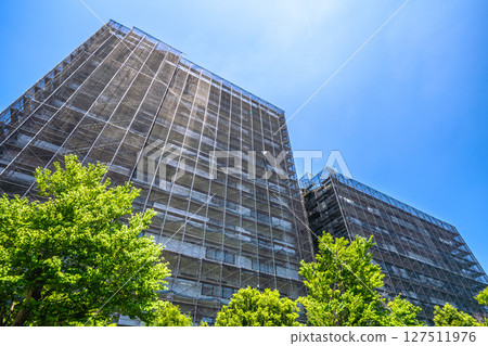 Yokohama cityscape in Japan. Apartment building repairs and inspections, scaffolding and protective nets. Satellite antennas outside the nets... 127511976