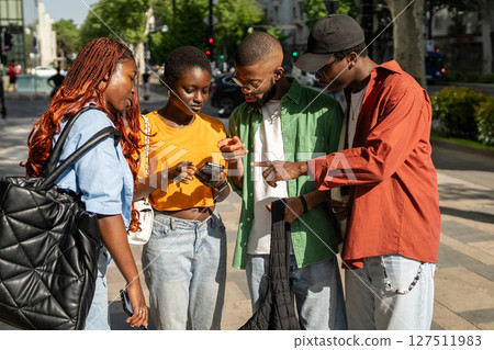Group of buddies students looking at phone screen with interest, checking, searching info online. 127511983