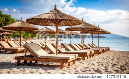 Tropical beach vacation with lounge chairs, umbrella, and clear blue sky over the ocean 127512146
