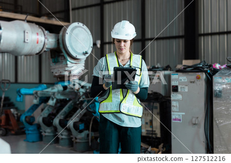 Robotic engineer women automatic mechanic using laptop checking quality system of automation robot arms machine in factory. Service programming machinery welding robots in production at factory. 127512216