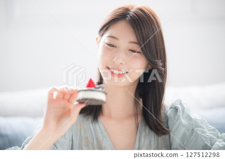 A woman eating sweet desserts with a smile. Sweets are a separate stomach A woman eating sweet desserts with a smile. Sweets are a separate stomach 127512298