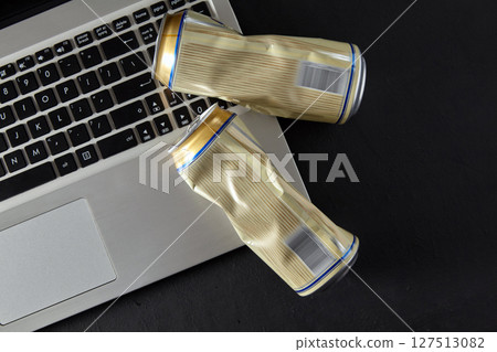 two empty crumpled aluminum beer cans lie on the laptop keyboard 127513082