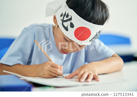 A child studying while wearing a "Hissho Hachimaki" (a Japanese traditional headband for winning) 127513341