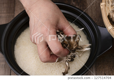 The process of making mushroom rice: Putting mushrooms on top of rice in a clay pot The process of making mushroom rice: Putting mushrooms on top of rice in a clay pot 127514704