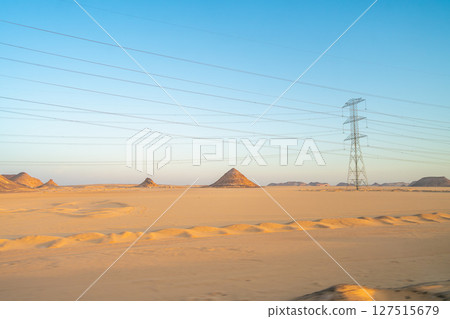 Power Lines Stretching Across the Desert Landscape at Sunrise in Aswan, Egypt. 127515679