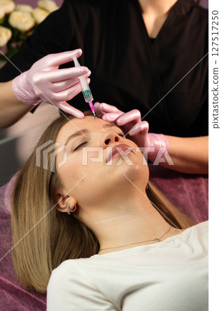 Practitioner apply patient's forehead with mesotherapy serum 127517250