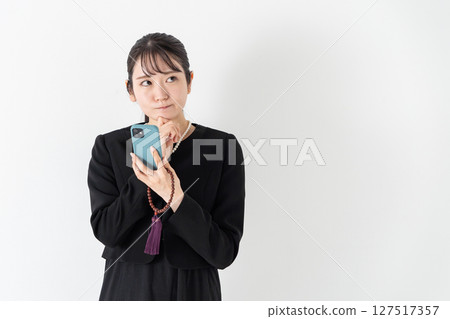 Woman in mourning clothes worries about smartphone Woman in mourning clothes worries about smartphone 127517357