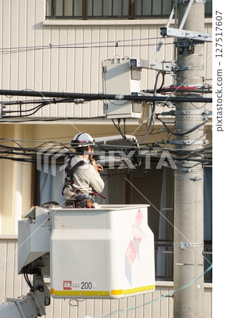 一名男子在升降車上進行電氣工作 一名男子在升降車上進行電氣工作 127517607
