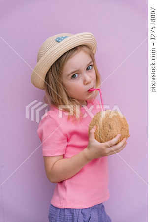 Young girl enjoying a coconut drink on a pastel background in summer 127518007