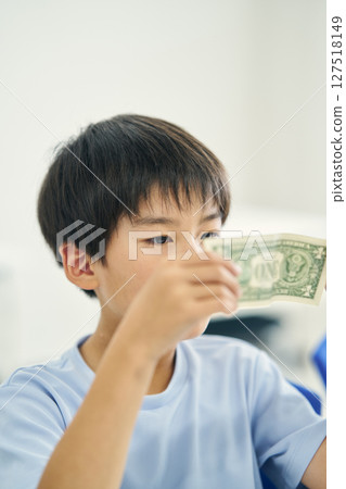 Elementary school student looking at banknotes Elementary school student looking at banknotes 127518149