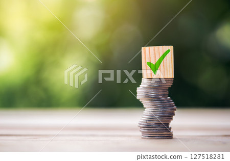 Loan approved to reduce debt: Coins stacked high on the table and wooden block approval symbols Risky loan approval concept. Loan approved to reduce debt: Coins stacked high on the table and wooden block approval symbols Risky loan approval concept. 127518281