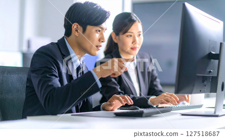 Business scene, businessman and businesswoman having a meeting while looking at a computer screen in the office 127518687