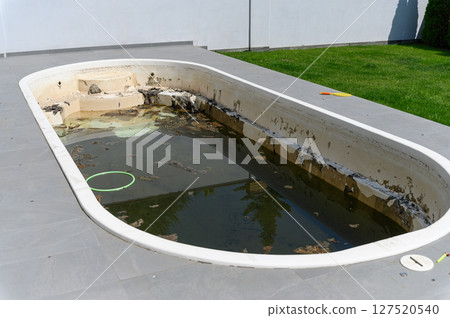 Dirty abandoned swimming pool with stagnant water and debris. 127520540
