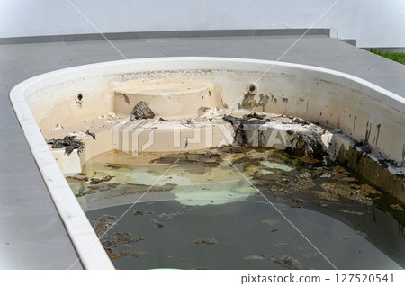 Dirty abandoned swimming pool with stagnant water and debris. 127520541