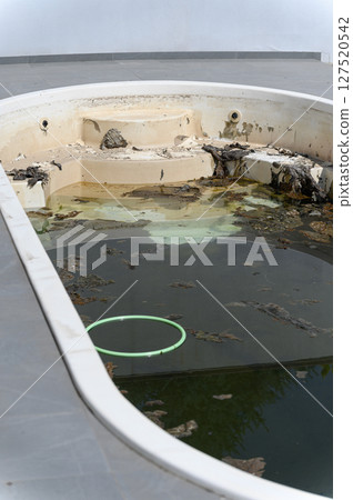 Dirty abandoned swimming pool with stagnant water and debris. 127520542