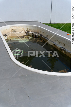 Dirty abandoned swimming pool with stagnant water and debris. Dirty abandoned swimming pool with stagnant water and debris. 127520543
