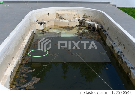 Dirty abandoned swimming pool with stagnant water and debris. Dirty abandoned swimming pool with stagnant water and debris. 127520545