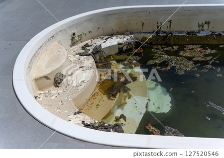 Dirty abandoned swimming pool with stagnant water and debris. Dirty abandoned swimming pool with stagnant water and debris. 127520546