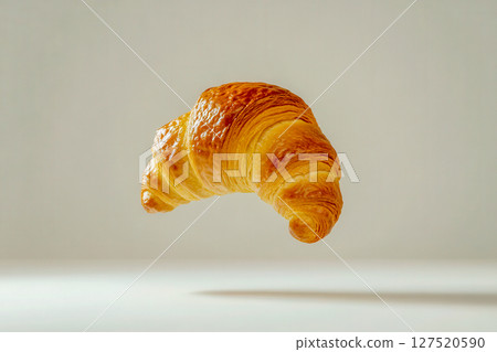 Croissant floating in mid-air showcasing its golden-brown texture with a minimalist background 127520590