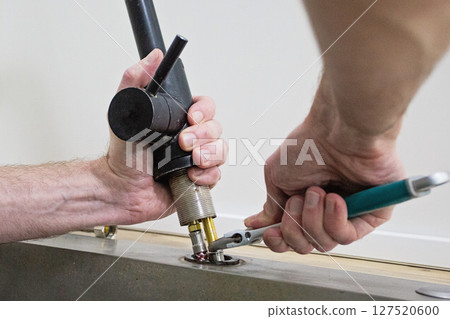 Plumber fixing kitchen faucet, close up 127520600
