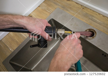 Plumber fixing sink faucet in bathroom. Featuring faucet and plumbing tools 127520602