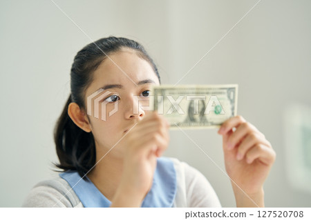 Elementary school student looking at banknotes 127520708