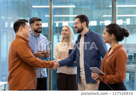 Diverse business team members shake hands in a modern office setting, symbolizing agreement and collaboration. Diverse business team members shake hands in a modern office setting, symbolizing agreement and collaboration. 127520919