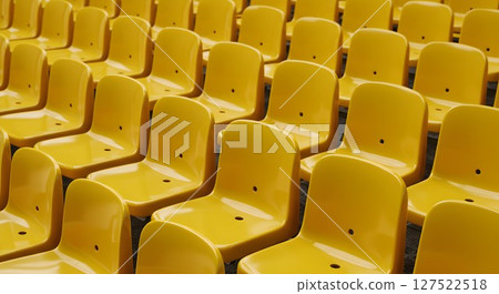 Rows of empty yellow stadium seats ready for an event. Grandstand seating for spectator sports, concert, or public gathering. 127522518