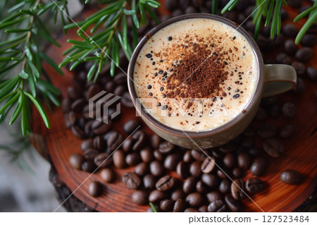 A rustic cup of freshly brewed coffee, sprinkled with cinnamon, roasted coffee beans and pine branches  A rustic cup of freshly brewed coffee, sprinkled with cinnamon, roasted coffee beans and pine branches  127523484